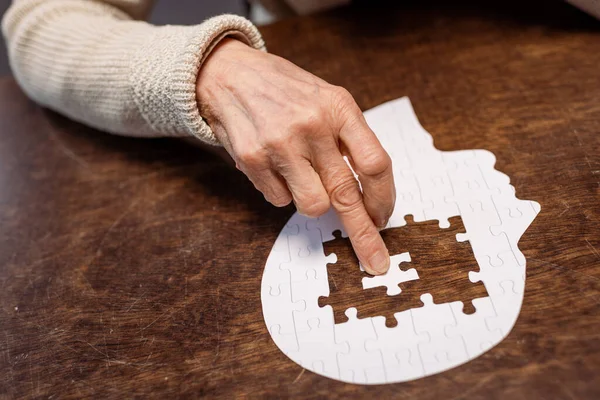 Partial view of woman combing jigsaw puzzle as dementia therapy — Stock Photo