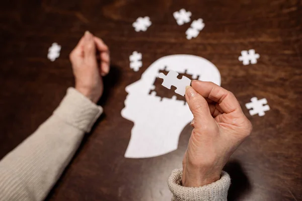 Cropped view of woman colleting jigsaw puzzle as dementia therapy — Stock Photo