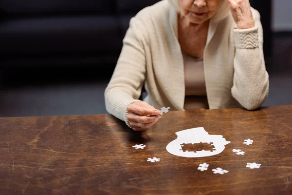 Senior woman collecting jigsaw puzzle as dementia therapy — Stock Photo