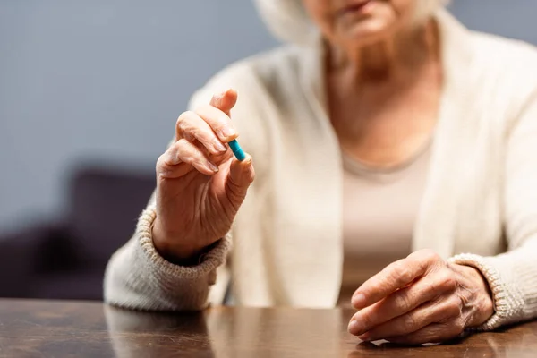 Partial view of senior woman holding pill, selective focus — Stock Photo