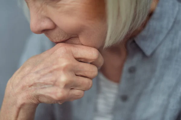 Vista recortada de la anciana mujer solitaria cogida de la mano cerca de la barbilla - foto de stock