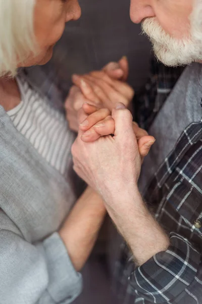 Vista recortada de la mujer mayor y su marido, enfermo de demencia, cogido de la mano - foto de stock