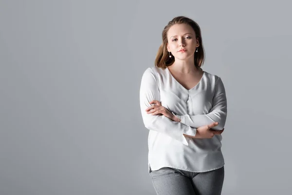 Attraente, fiduciosa ragazza in sovrappeso posa con le braccia incrociate isolato su grigio — Foto stock