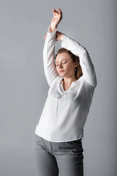 Елегантна дівчина з надмірною вагою позує із закритими очима і піднятими руками ізольовані на сірому — Stock Photo