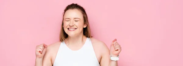 Immagine orizzontale di eccitata ragazza in sovrappeso che mostra il gesto del vincitore sul rosa — Foto stock