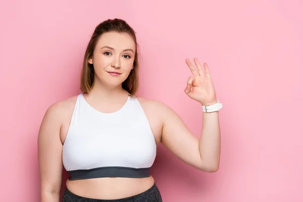 Sonriendo chica con sobrepeso mostrando gesto bien en rosa - foto de stock