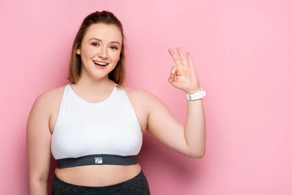 Feliz chica con sobrepeso mostrando gesto bien en rosa - foto de stock