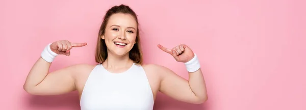 Panoramische Ernte eines fröhlichen übergewichtigen Mädchens, das mit den Fingern auf sich selbst auf rosa zeigt — Stockfoto