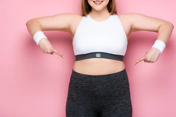 Abgeschnittene Ansicht eines lächelnden übergewichtigen Mädchens, das mit den Fingern auf sich selbst auf rosa zeigt — Stockfoto