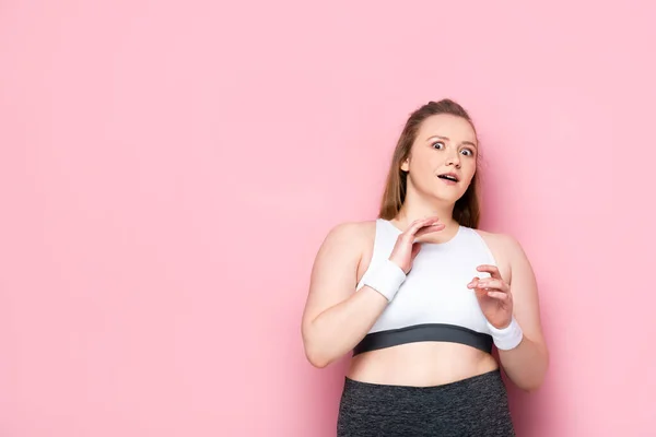 Verängstigtes übergewichtiges Mädchen gestikuliert, während es in die Kamera auf rosa schaut — Stockfoto