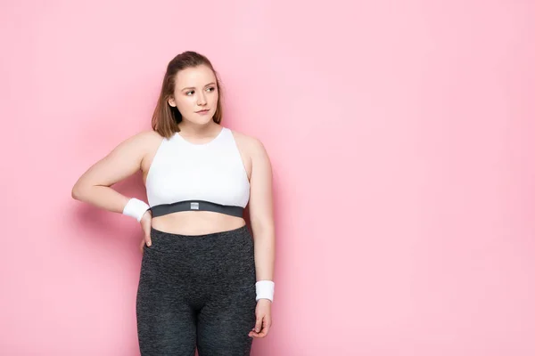 Schweres übergewichtiges Mädchen, das die Hand an der Hüfte hält, während es auf rosa wegsieht — Stockfoto