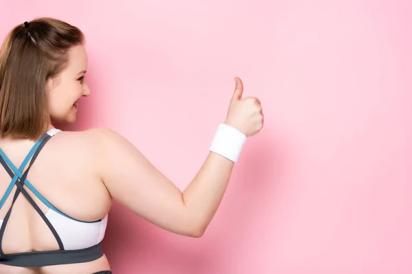 Rückseite des übergewichtigen Mädchens zeigt Daumen nach oben auf rosa — Stockfoto