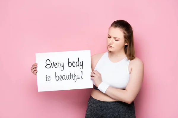 Serious overweight holding placard with every body is beautiful inscription on pink — Stock Photo