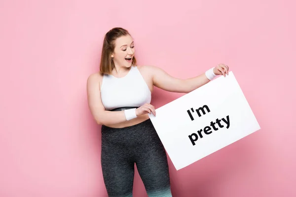 Excited overweight girl holding placard with i am pretty inscription on pink — Stock Photo