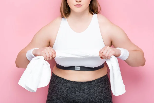 Cropped view of overweight girl in sportswear holding white towel on pink — Stock Photo