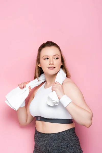 Chica bastante obesa limpiando el cuello con toalla mientras mira hacia otro lado en rosa - foto de stock