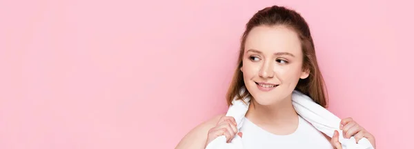 Lächelndes Plus-Size-Mädchen mit Handtuch am Hals, das wegschaut und isoliert auf rosa lächelt — Stockfoto