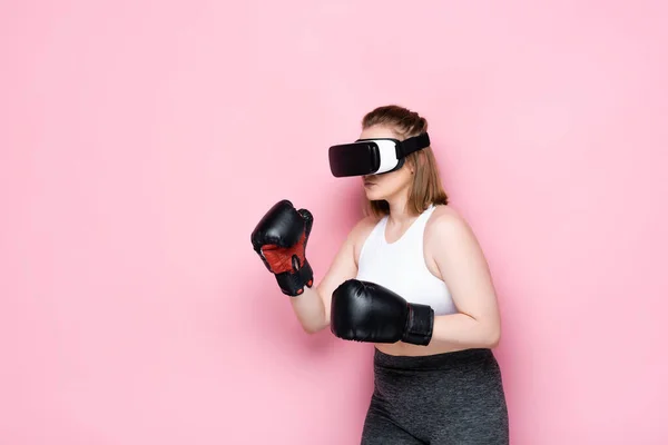 Overweight girl in boxing gloves using vr headset on pink — Stock Photo