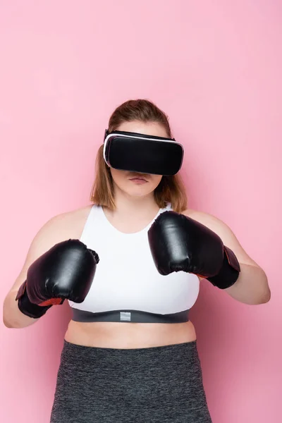 Taglia plus ragazza in abbigliamento sportivo, auricolare vr e guanti da boxe su rosa — Foto stock