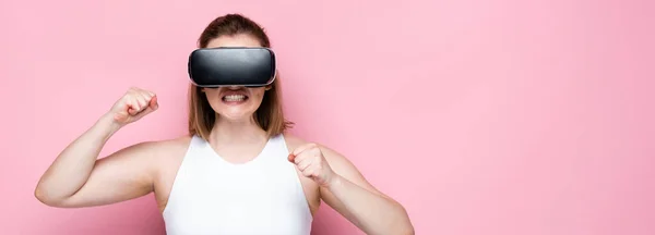 Imagem horizontal de menina com sobrepeso agressivo em sportswear e vr fone de ouvido com punhos apertados em rosa — Fotografia de Stock