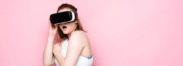 Horizontal image of scared overweight girl in vr headset and sportswear on pink — Stock Photo