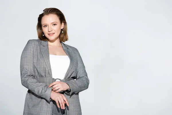 Красивая, стильная девушка plus size улыбается на камеру, позируя в одиночестве на сером фоне — Stock Photo