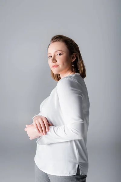 Elegant, confident plus size girl looking at camera while posing isolated on grey — Stock Photo