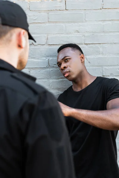 Foco seletivo do homem afro-americano assustado olhando para policial, conceito de racismo — Fotografia de Stock