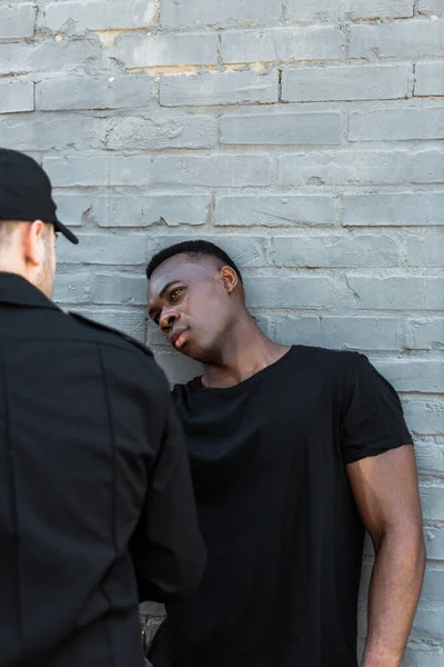 Focalizzazione selettiva dell'uomo africano americano preoccupato guardando poliziotto, concetto di razzismo — Foto stock