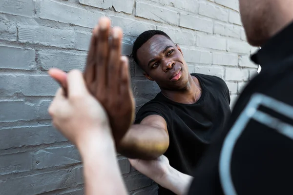 Foco seletivo do homem afro-americano ferido olhando para a mão tocando policial, conceito de racismo — Fotografia de Stock