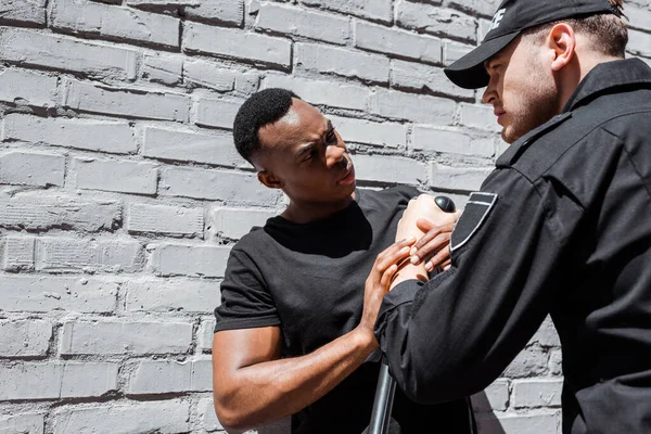 Angry police officer detaining african american man on street, racism concept — Stock Photo