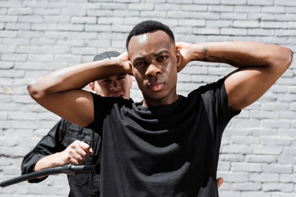 Policía con bastón policial que detiene a afroamericano en la calle, concepto de racismo — Stock Photo