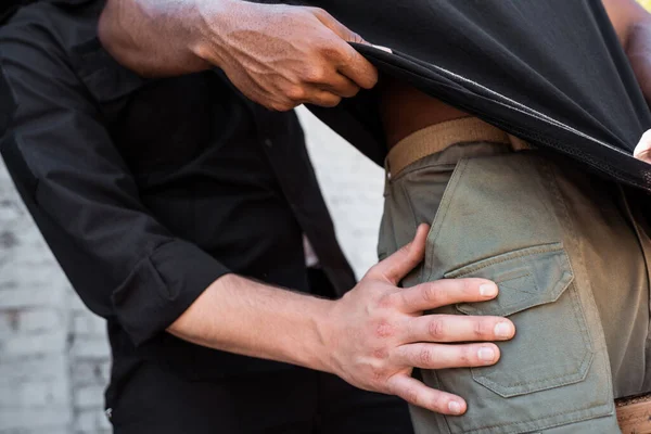 Abgeschnittene Ansicht eines Polizisten, der Kleidung eines Afroamerikaners berührt — Stockfoto