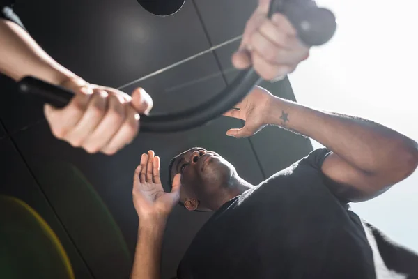 Bottom view of police officer holding truncheon near tattooed african american man, racism concept — Stock Photo