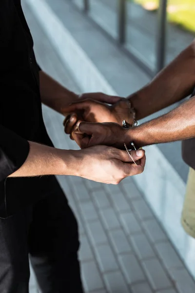 Abgeschnittene Ansicht eines Polizisten, der die Hände eines gefesselten Afroamerikaners berührt — Stockfoto