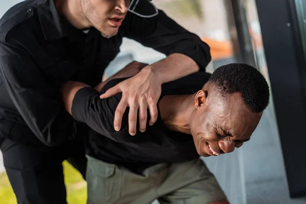 Wütender Polizeibeamter nimmt Afroamerikaner fest, der unter Schmerzen und Rassismus leidet — Stockfoto