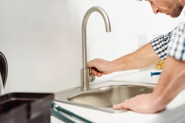 Cropped view of plumber fixing faucet near toolbox in kitchen — Stock Photo