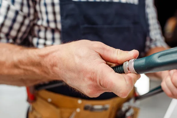 Ausgeschnittene Ansicht eines Arbeiters in Overalls, der einen Rohrschlüssel in der Küche hält — Stockfoto