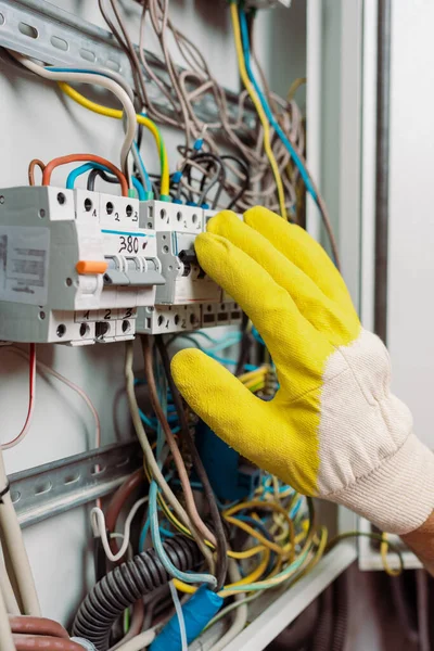 Vista cortada do eletricista em luva, incluindo interruptores de alternância do painel elétrico — Fotografia de Stock