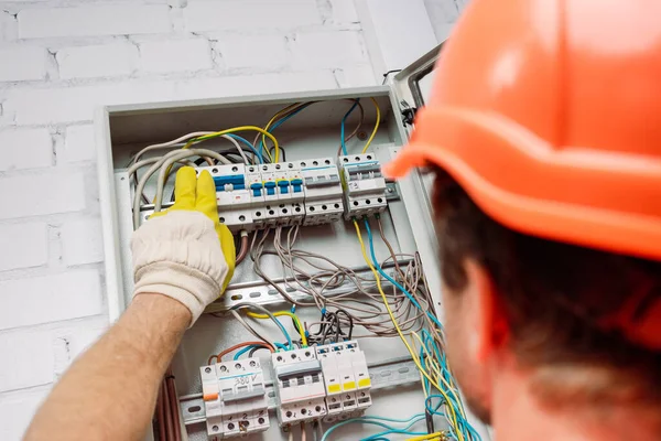 Mise au point sélective de l'électricien allumant les interrupteurs à bascule de la boîte de distribution électrique — Photo de stock