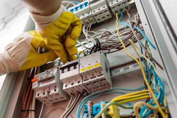 Low angle view of electrician in gloves fixing electrical distribution box — Stock Photo