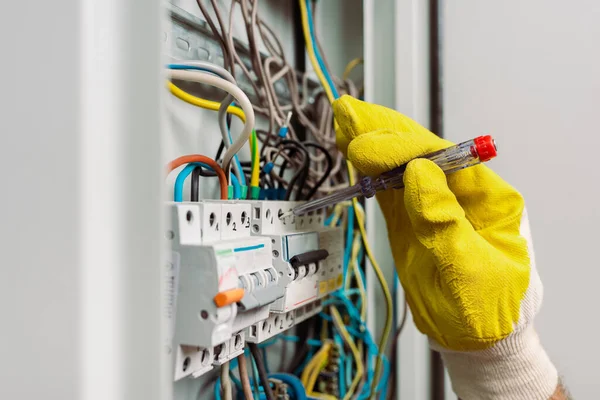 Mise au point sélective de l'électricien à l'aide d'un tournevis lors de la fixation du panneau électrique — Photo de stock