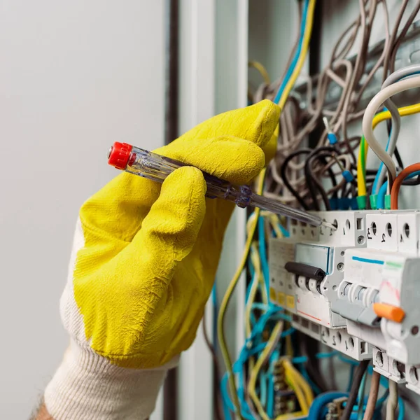 Ausgeschnittene Ansicht eines Elektrikers im Handschuh mit einem Schraubenzieher bei der Reparatur eines elektrischen Verteilerkastens — Stockfoto