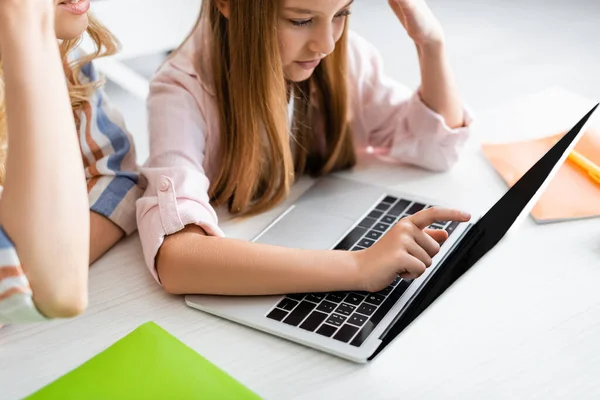 Selective focus of kid pointing with finger at laptop near mother at table — Stock Photo