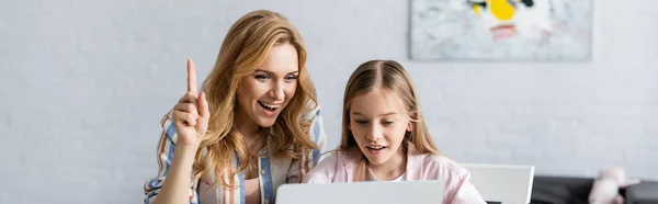 Imagen panorámica de la mujer sonriente que tiene idea mientras ayuda a su hija con la educación en línea - foto de stock