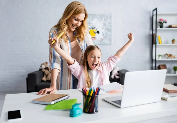 Enfoque selectivo de la madre sonriente mirando al niño alegre mostrando sí gesto durante la educación en línea - foto de stock