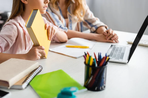 Vista ritagliata del libro per bambini durante l'apprendimento elettronico vicino alla madre a casa — Foto stock