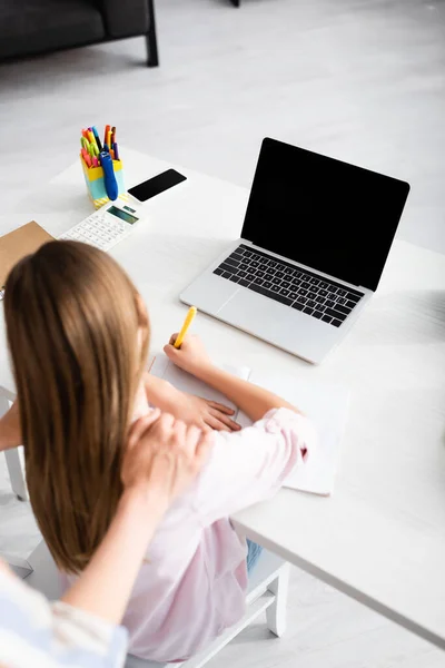 Vue aérienne de la femme embrassant l'enfant pendant l'éducation en ligne à la maison — Photo de stock