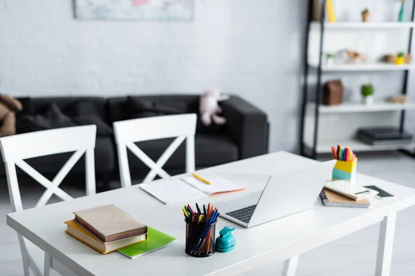 Enfoque selectivo de la computadora portátil, libros y papelería en la mesa en casa - foto de stock