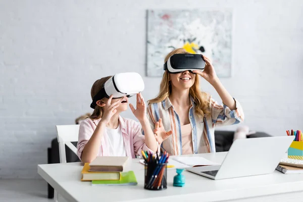 Selective focus of smiling mother and kid using vr headsets during online education at home — Stock Photo